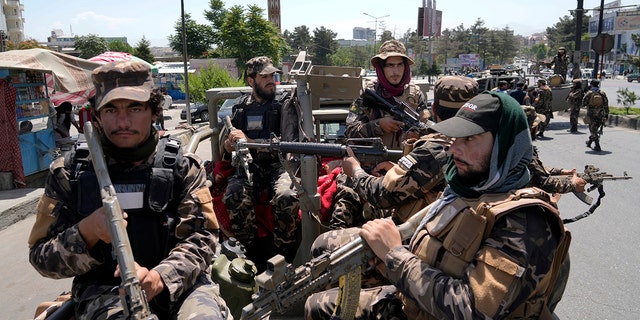 Taliban-Kämpfer bewachen die Explosionsstelle in Militäruniformen und mit Waffen