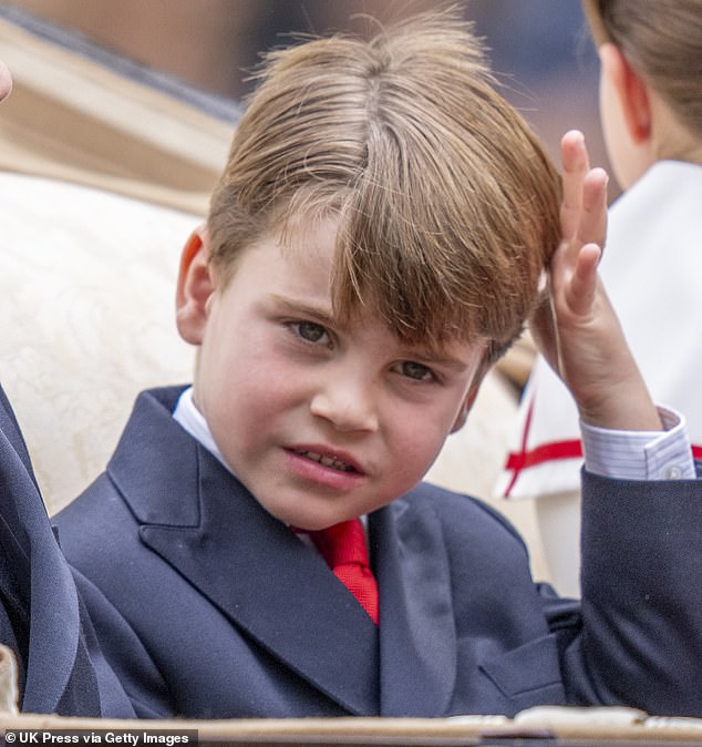 Prince Louis, five, is pictured as he travels along in a carriage with his siblings, Prince George and Princess Charlotte