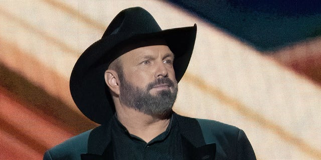 Garth Brooks trägt den charakteristischen schwarzen Hut und Mantel vor