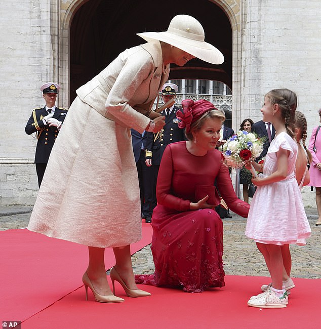 Königin Mathilde hockte tief auf dem Boden, während sie mit den Blumenmädchen plauderte und Poseys von ihnen entgegennahm