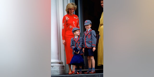 Prinzessin Diana in Rot steht neben Prinz William und Prinz Harry in Schuluniformen