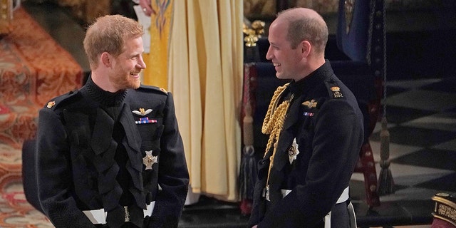 Prinz William und Prinz Harry lächeln sich in Anzügen mit Medaillen an