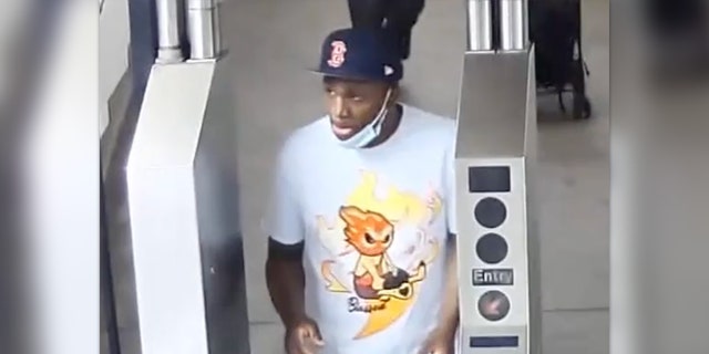 Der Verdächtige, der einen Hieb durchführt, trägt einen Hut der Boston Red Sox und ein weißes Graphic T und steht am Drehkreuz der New Yorker U-Bahn