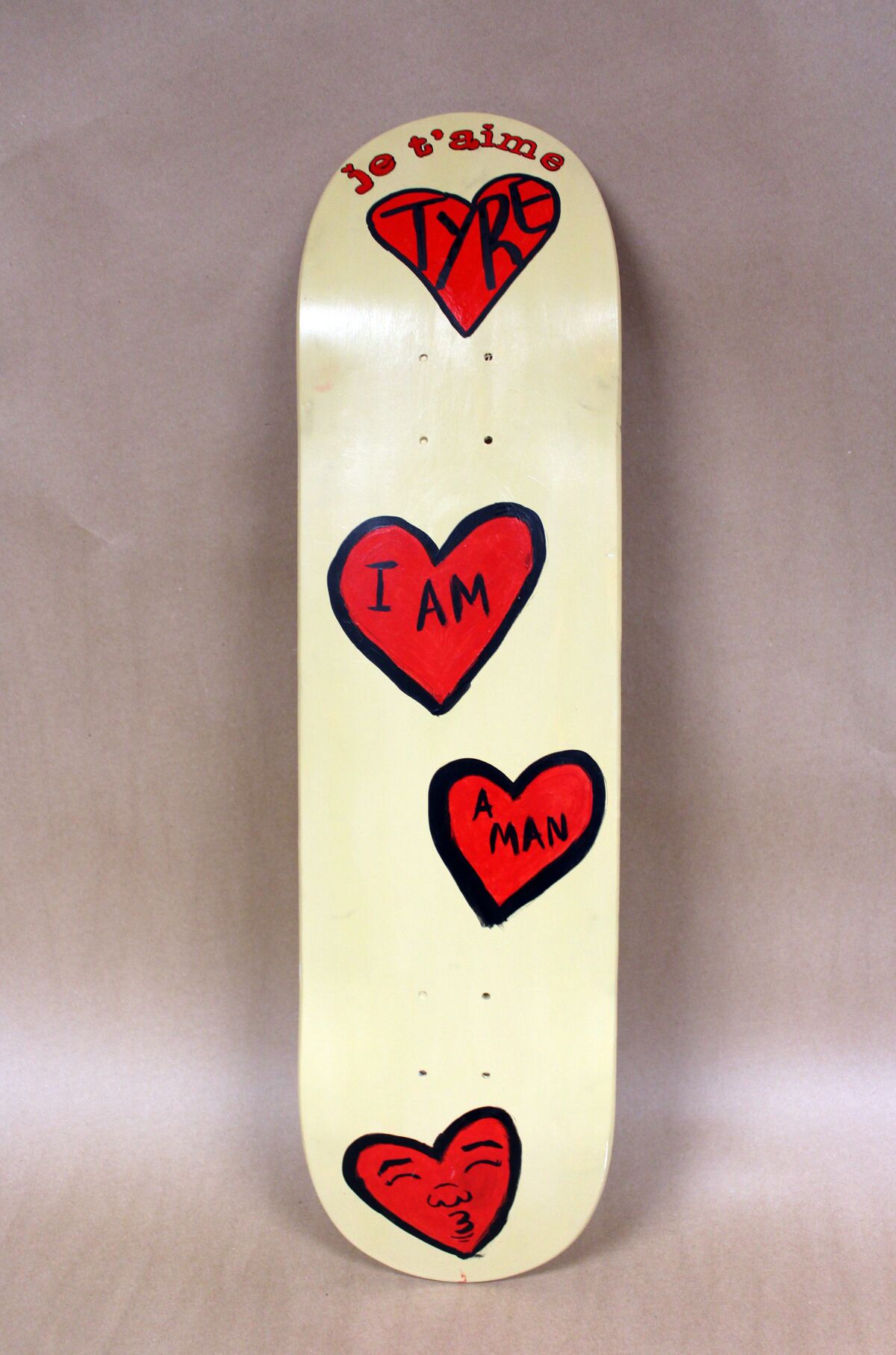 Auf einem Skateboard mit roten Herzen steht: "Je t'aime Tyre" Und "Ich bin ein Mann."