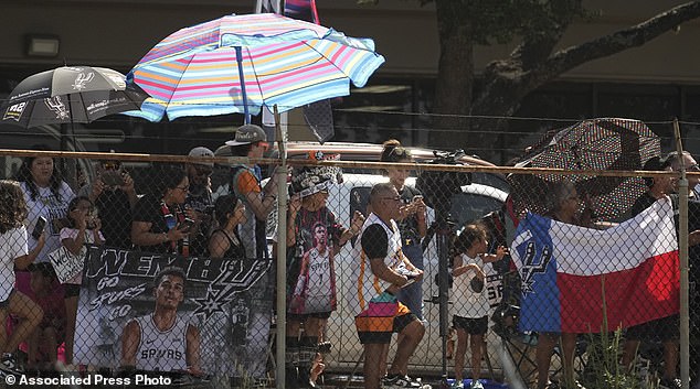 Fans versammeln sich hinter einem Zaun, um zuzusehen, wie Wembanyama am Freitag am Flughafen von San Antonio ankommt