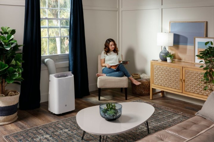 Die tragbare 10.000-BTU-Klimaanlage von GE kühlt ein Wohnzimmer, während eine Frau liest.