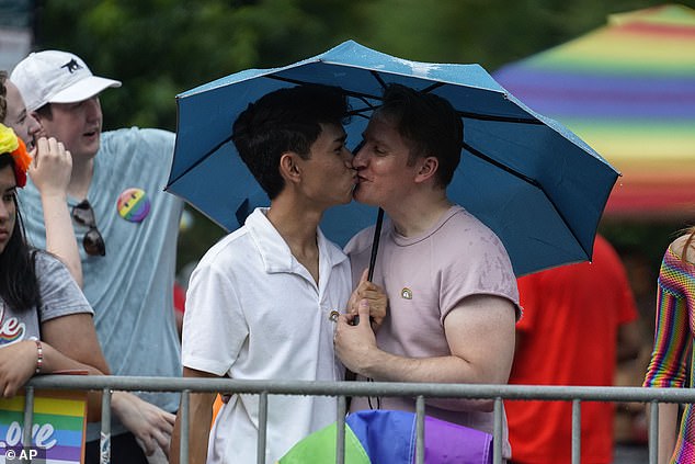 Jon Batayola, left, and Daniel Biginton embrace under an umbrella as they await the beginning of Chicago's annual Pride Parade