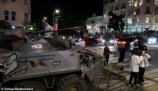 This image captured from a video shows citizens standing near military vehicles on a street of Rostov-on-Don, Russia, on June 24, 2023