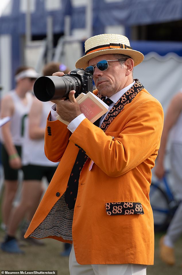 Ein Gast trug einen leuchtend orangefarbenen Blazer, den er mit einem Strohhut und einer weißen Hose kombinierte
