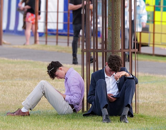 Two racegoers sat on the floor, gazing at their phones as they contemplated how to get home