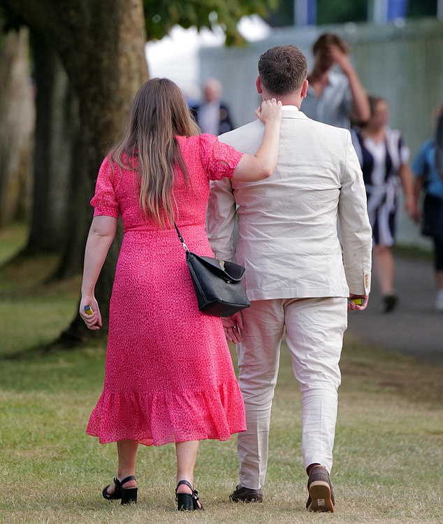 A racegoer in a pink dress put a guiding hand on her partner's collar as they left the party