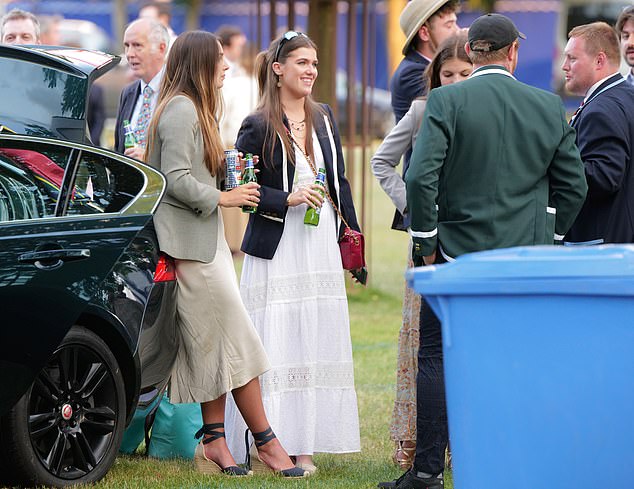 Two glamourous racegoer chatted with friends while finishing their beers in the car park