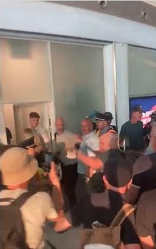 Taylor (im Bild links in einem dunkelgrauen Hemd) wurde von einer großen Gruppe angesprochen, als er durch den Flughafen ging