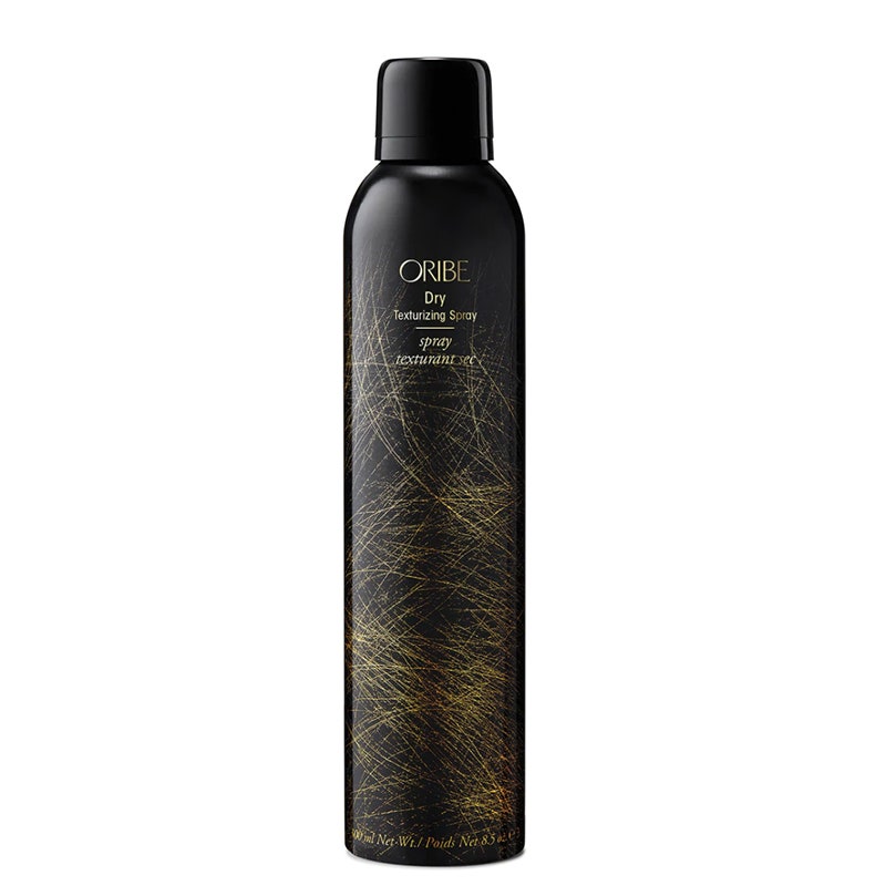 Eine schwarz-goldene Flasche des Oribe Dry Texturizing Spray auf weißem Hintergrund
