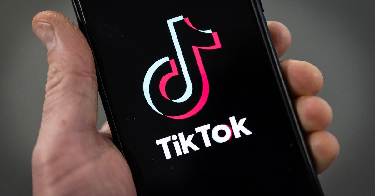 Eine Person mit einem Smartphone, auf dem das Logo von TikTok zu sehen ist