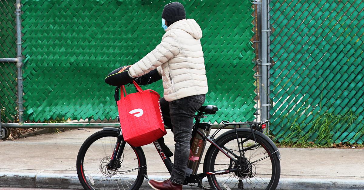Eine Person, die auf einem Fahrrad eine DoorDash-Lieferung durchführt
