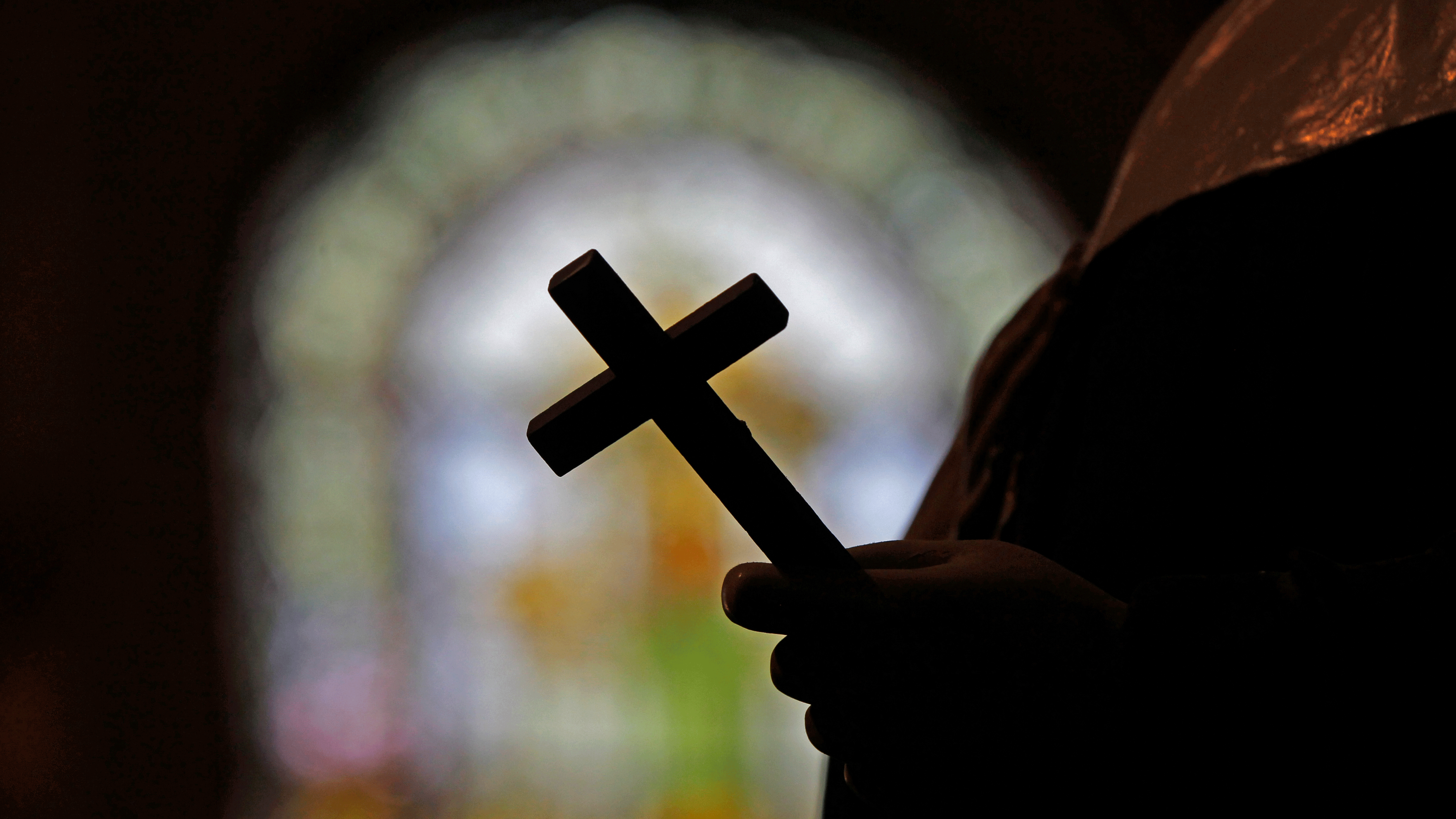 Priester hält Kreuz