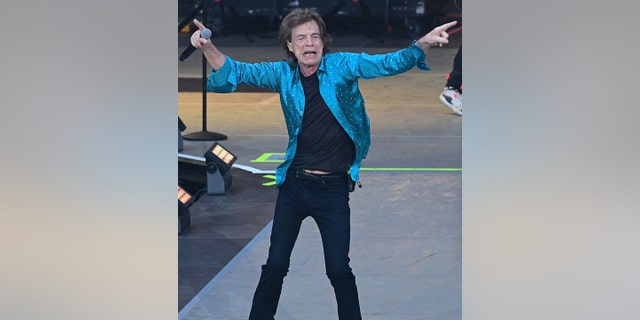 Mick Jagger in Berlin beim Auftritt mit den Rolling Stones, die auf der Bühne in entgegengesetzte Richtungen zeigen