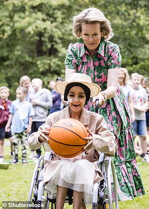 Die Königin wurde abgebildet, wie sie ein junges Mädchen im Rollstuhl schob, das einen Basketball in der Hand hielt, während die Gruppe an einigen Spielen teilnahm