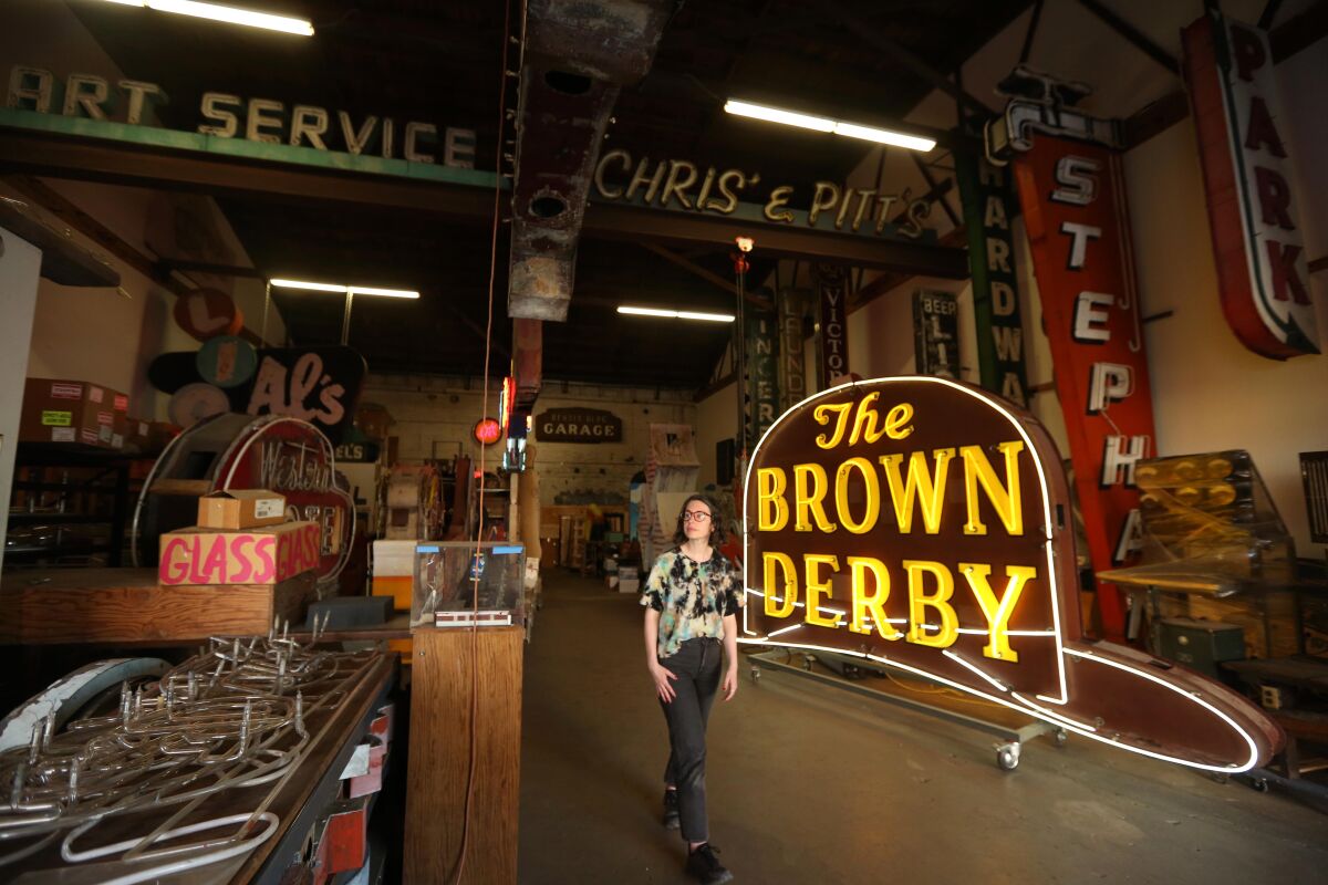 Eine Frau steht vor einem "Das Brown Derby" Neonschild 