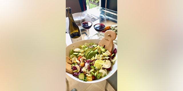Brooke Burkes Junk-Salat neben einem Glas und einer Flasche Wein