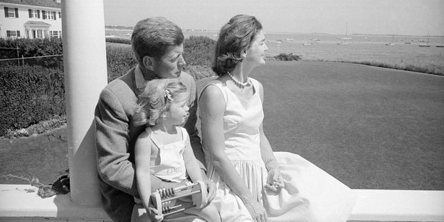 John F. Kennedy hat Caroline auf seinem Schoß, die mit Jackie auf das Kap blickt