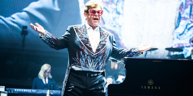 Elton John steht mit Sonnenbrille auf der Bühne