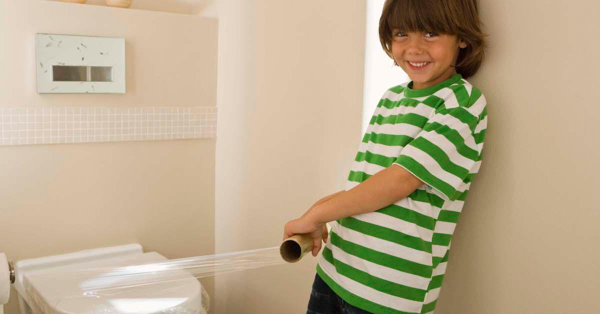 Ein Kind legt Plastikfolie auf eine Toilette