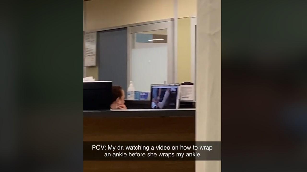Ein Mann sah, wie sein Arzt sich vor der Behandlung seines Knöchels ein Video über die Knöchelwickelung ansah