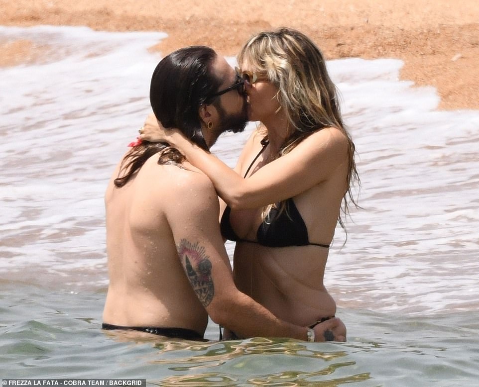 Kissy time: The two put their arms around each other then kissed as they splashed around in the ocean while trying to cool off during an intense heat wave