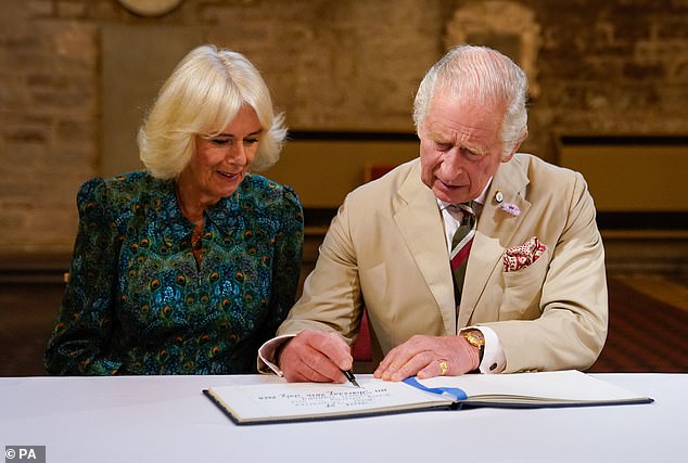 King Charles and Queen Camilla pictured signing the visitors book during a visit to Brecon Cathedral today