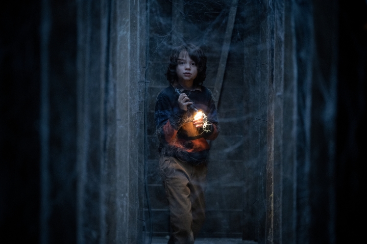 Woody Norman hält eine Taschenlampe in einem dunklen Kriechkeller in Cobweb.