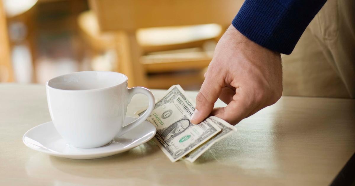 Mann hinterlässt Trinkgeld für eine Tasse Kaffee auf dem Tisch im Café