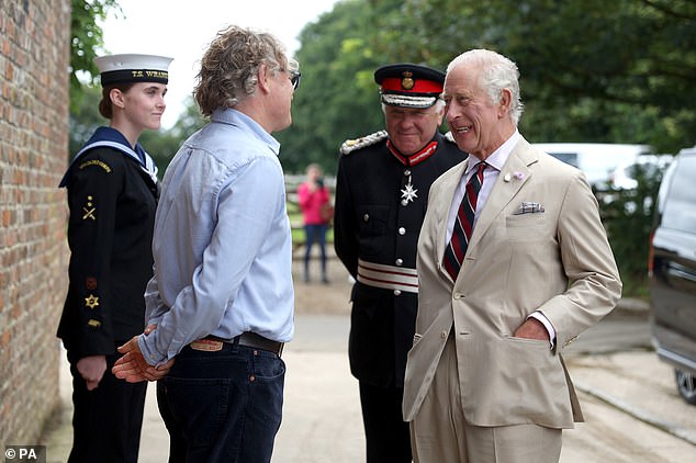 King Charles pictured speaking with farmer Simon Jones as he arrived for the tour of the environmentally-friendly business