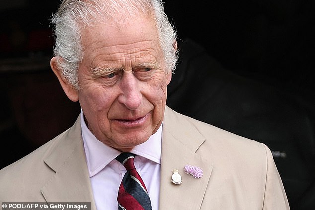 King Charles wore a purple flower on his lapel and a red-and-navy striped tie for his engagement today