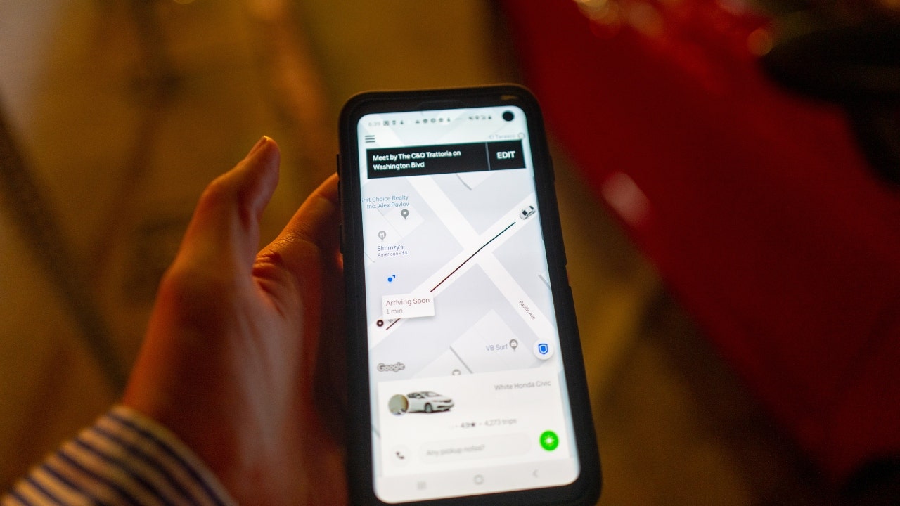 Eine Frau hält ein Smartphone hoch, auf dem die Uber-App zu sehen ist