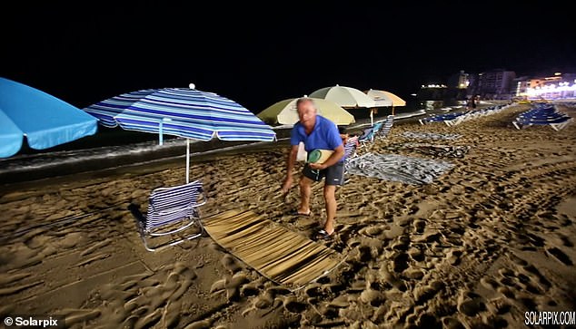 As the waves crash against the beach in the dead of night, a desperate man can be seen in one video unravelling a beach mat with a deadly serious look painted across his face