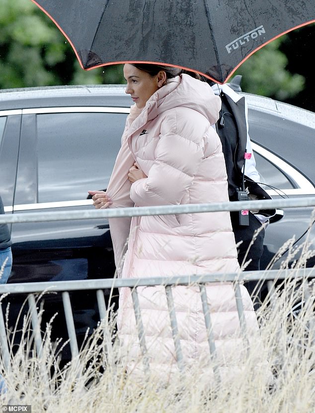 Keeping warm: The former Coronation Street star walked to set under an umbrella which a crew member carried over her