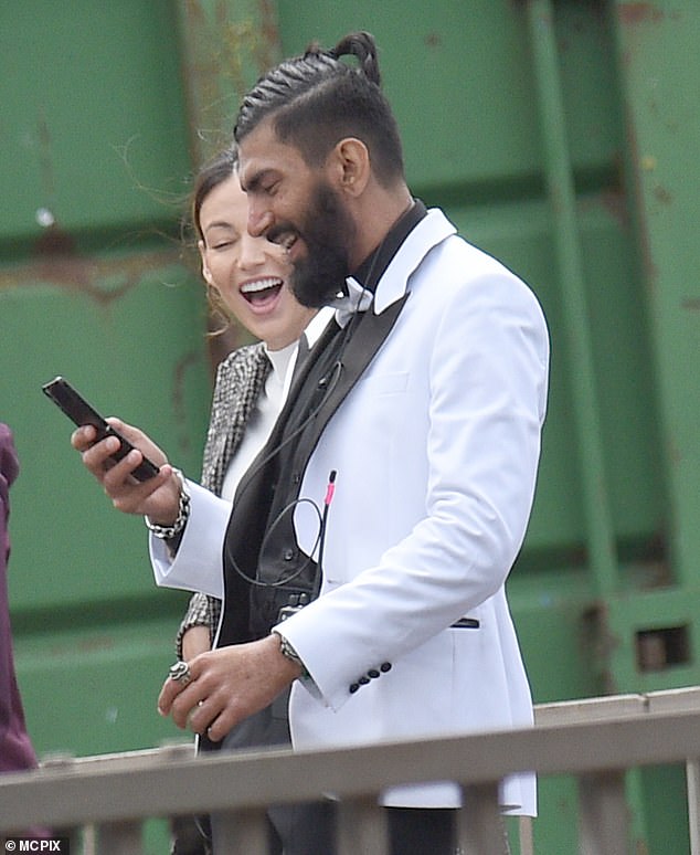 Sensational: Michelle couldn't contain her smile as she looked at a crew members phone on the way to set