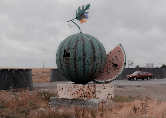 an aged watermelon sculpted from metal with bullet holes