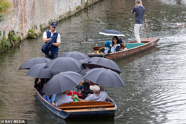 Tourists huddled under umbrellas and blankets as they went for a punt on the River Cam in Cambridge on Monday afternoon