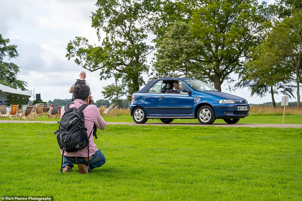 A showgoer snaps a photo of a Fiat Punto Cabriolet passing on entry to the Grimsthorpe Castle grounds on Saturday