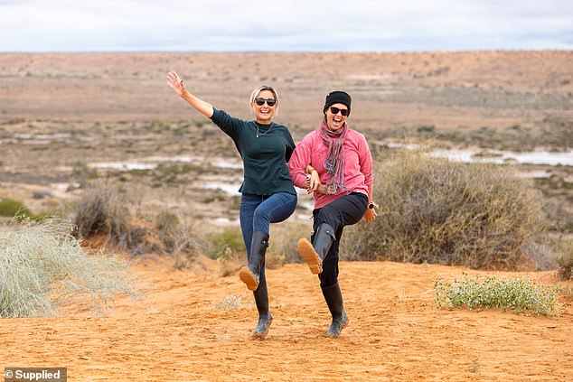Über 10.000 Feiernde, die zum abgelegensten Musikfestival der Welt unterwegs sind, haben sich geweigert, eine seltene Sintflut tief in der australischen Wüste auf ihre Parade regnen zu lassen.  Im Bild: Zwei Frauen tanzen auf der Spitze der großen roten Sanddüne in der Simpson-Wüste (Bildnachweis: Matt Williams)