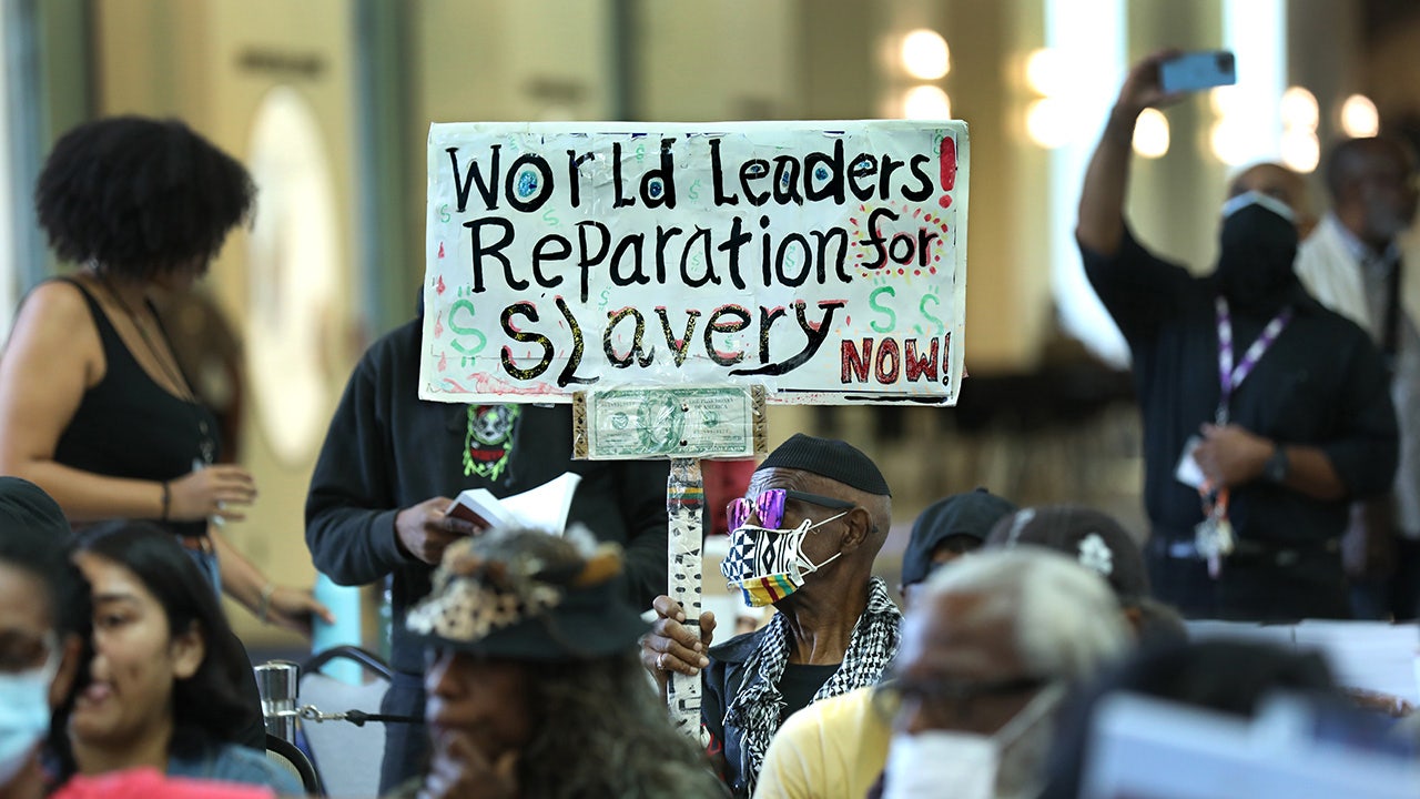 Ein Einwohner von LA hält ein Schild hoch, auf dem er Wiedergutmachung für die Sklaverei fordert