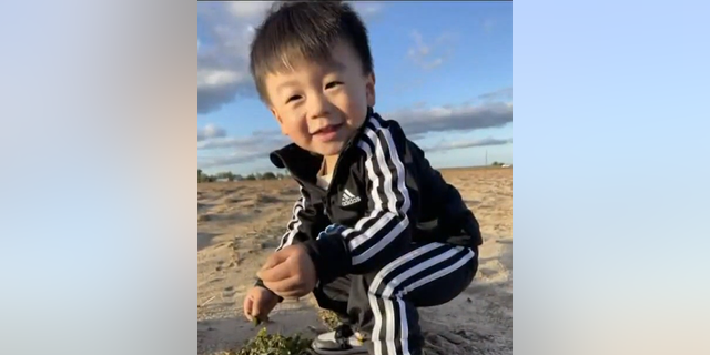 Jasper Wu hockt und lächelt am Strand