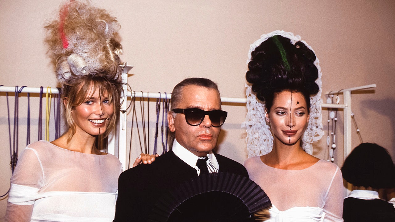 Claud Schiffer in white and teased hair and Christy Turlington in white and slightly less teased hair sandwhich Karl Lagerfeld for a photo in Paris