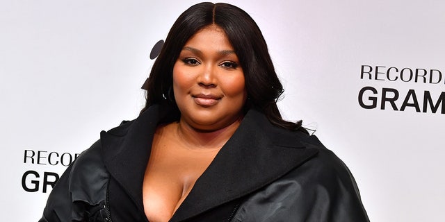 Lizzo smiles at The GRAMMY Museum in Los Angeles in a black low-cut outfit