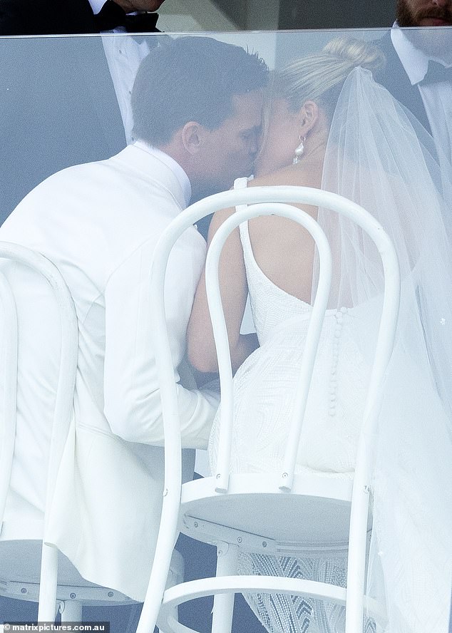 The couple continued to exchange smooches as they sat side by side on white chairs at their reception