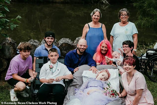 A heartwarming family photo during the June wedding with DJ sat beside the bride