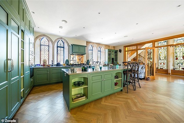 Die weitläufige Küche verfügt über grüne Unter- und Oberschränke sowie dekorativere Bogenfenster